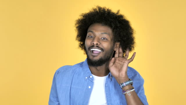 Afro-amerikanischer-Mann-hören-Geheimnis-stehen-auf-gelbem-Hintergrund
