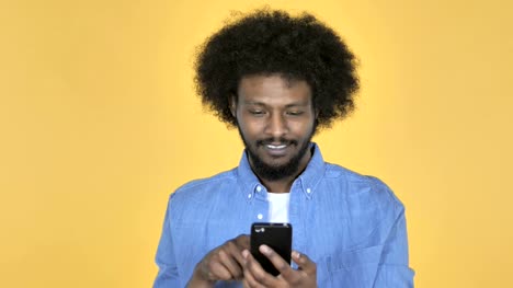 Afro-amerikanischer-Mann-Surfen-Smartphone-auf-gelbem-Hintergrund