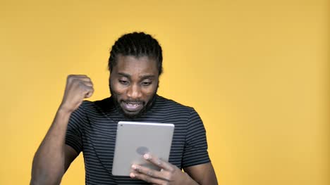 Lässige-afrikanischen-Mann-begeistert-für-den-Erfolg-bei-der-Verwendung-von-isolierten-Tablet-auf-gelbem-Hintergrund