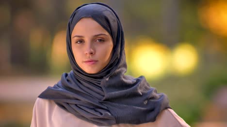 Close-up-portrait-of-Muslim-girl-in-hijab-watching-into-camera,-modestly-nodding-to-show-agreement.