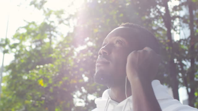 Hombre-africano-con-auriculares-disfrutando-de-días-soleados-y-sonriendo-a-cámara