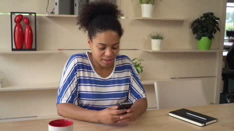 Glücklich-Frau-benutzt-app-auf-Mobiltelefon-im-Büro