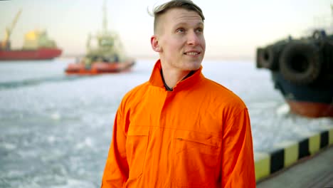 Dock-Arbeiter-in-orange-Uniform-mit-Blick-auf-das-Meer-und-die-Landschaft-des-Hafens-im-Winter-zu-genießen.-Vereisten-See