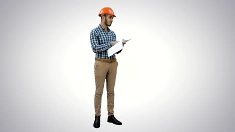 Junger-Ingenieur-im-Helm-überprüfen-Konstruktionszeichnungen-auf-weißem-Hintergrund