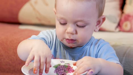 An-attractive-boy-2-years-old-is-eating-red-soup-himself.-The-bay-leaf-caught-in-a-plate-and-the-kid-plays-with-it