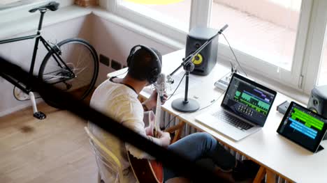 black-man-creative-musician-at-home-studio-works-by-playing,singing-and-recording-guitar-with-notebook-tablet-and-microphone-indoor-in-modern-industrial-house.-4k-handheld-top-view-overhead-video-shot