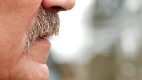 Ein-älterer-Mann-mit-einem-Schnurrbart-raucht-eine-Zigarette-vor-dem-Filter.-Nahaufnahme-von-Mund-und-Zigarette