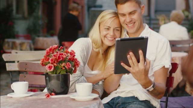 Joven-pareja-sonriendo-con-Tablet-PC-en-tienda-de-café
