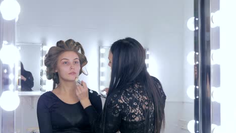 Make-up-Artist-Anwendung-flüssiger-klangliche-Fundament-auf-Gesicht-der-Frau