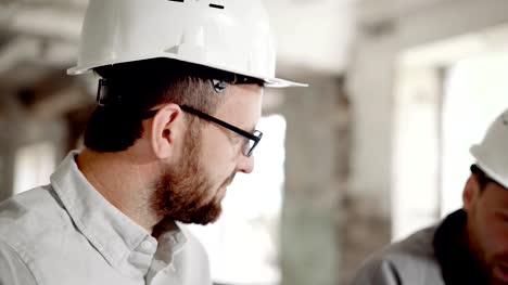 Portrait-of-a-satisfied-businessman-in-a-helmet-on-his-head,-who-discusses-the-completion-of-the-construction-site-with-a-foreman