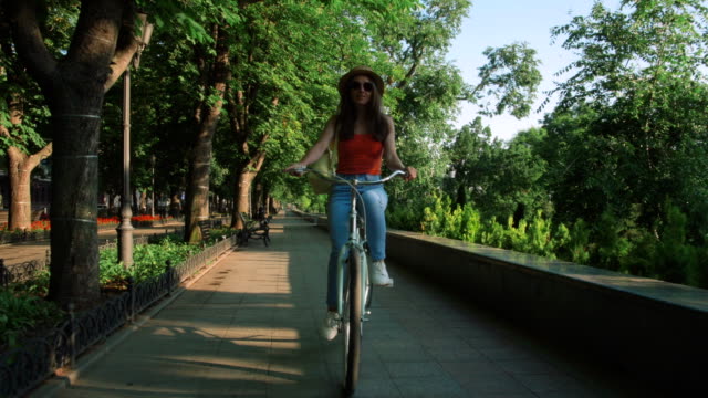 joven-hermosa-mujer-montando-una-bicicleta-en-un-parque
