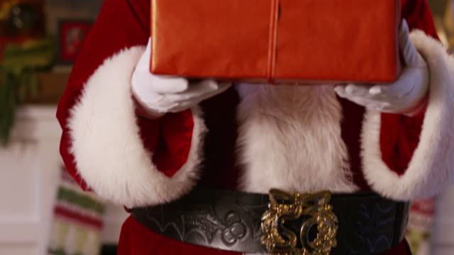 Santa-Claus-peeks-out-from-behind-stack-of-gifts