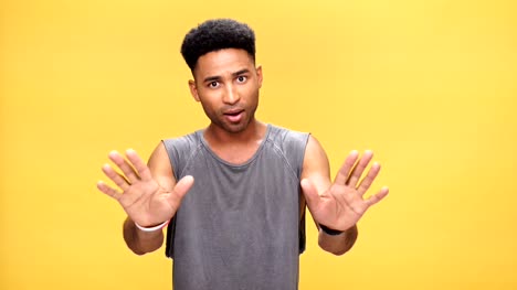 Young-nervous-african-man-says-stop-to-you-over-yellow-background.