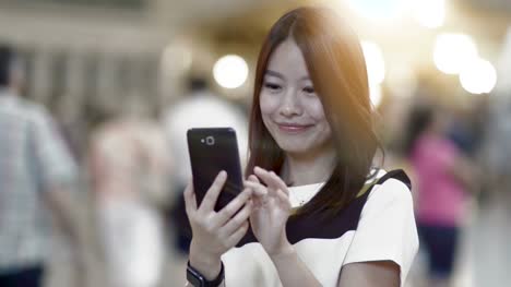 Attractive-Asian-Woman-Using-Phone-in-the-City.-Dark-Eyes-and-Dark-Hair.-Crowded-and-Urban-Background.
