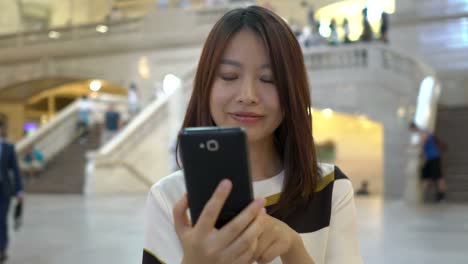 Hermosa-mujer-China-enviar-mensajes-de-texto-y-hablando-con-el-teléfono-en-el-espacio-público.-Ser-feliz,-sonreír-y-divertirse.