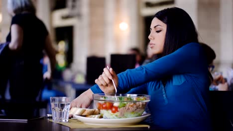 schöne-philippinische-Frau-Essen-einen-Salat-und-auf-Handy-lesen