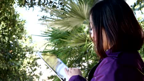 Young-Chinese-woman-using-the-tablet-looks-around-and-smiles,portrait