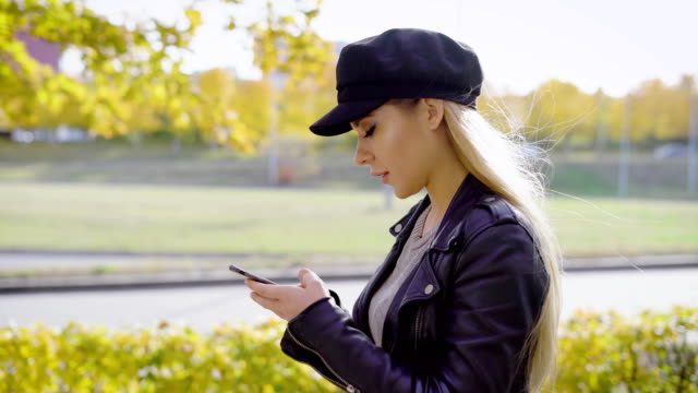 Joven-modelo-elegante-con-paseo-en-el-parque-urbano-con-smartphone
