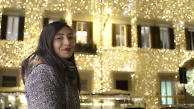 glückliche-Frau-lächelt-in-die-Kamera-mit-beleuchteten-Palast-im-Hintergrund