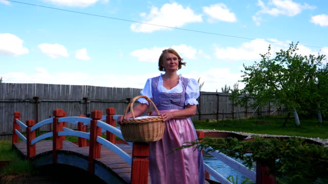 Eine-Frau-in-ein-nationales-Kostüm-steht-eine-schöne-Brücke-über-einen-Teich.