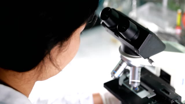 Female-scientist-looking-microscope-eyepiece