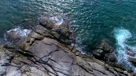 Aerial:-Two-partners-doing-Acro-Yoga-on-the-rocks-near-the-sea.