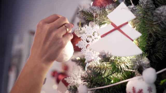 Eine-junge-Prettty-Frau-schmückt-einen-Weihnachtsbaum-mit-Spielzeug