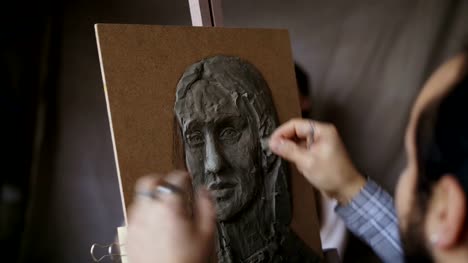 Nahaufnahme-des-Bildhauers-erstellen-Skulptur-des-menschlichen-Gesichts-auf-Leinwand-im-Atelier