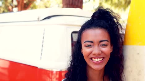 Smiling-woman-with-surfboard-standing-near-camper-van-4k