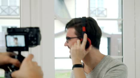 Proceso-de-filmar-vídeo-con-joven-hombre-escuchar-música-en-auriculares