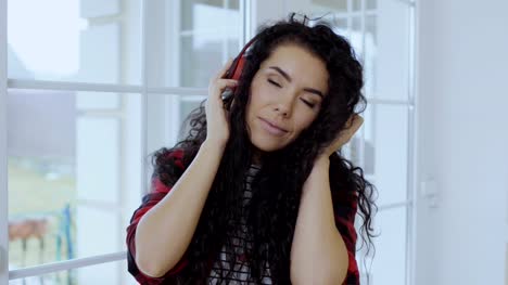 Beautiful-curly-brunette-with-red-lips-enjoys-of-listening-music-in-headphones