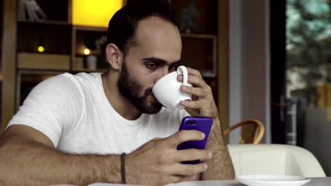 Hombre-usando-app-smartphone-tomando-café,-mensajes-de-texto-en-el-teléfono-móvil
