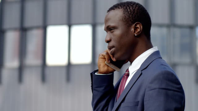 profile-of-young--black-business-man-talking-by-phone-in-the-street