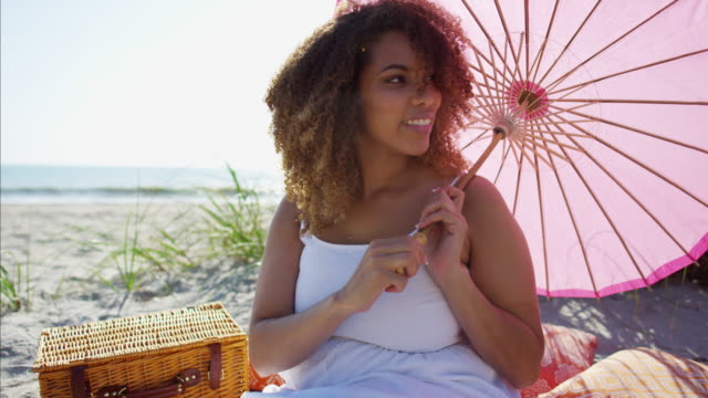 African-American-female-enjoying-picnic-by-sand-dunes