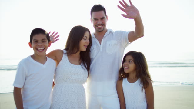Portrait-of-Spanish-family-waving-hands-on-holiday