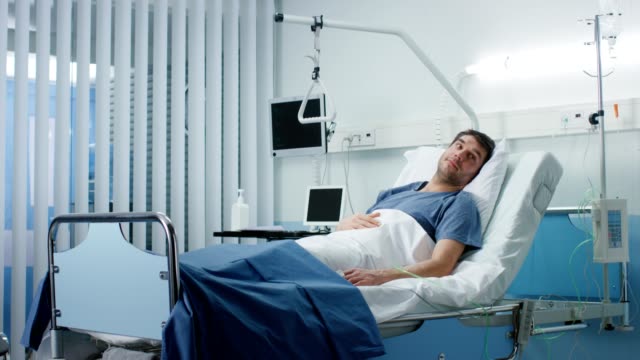 Kranke-männliche-Patient-liegend-auf-einem-Bett-im-Krankenhaus.-Saubere-und-ruhige-klinische-Ward.