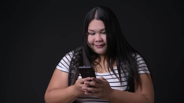 Schöne-Übergewicht-asiatische-Frau-mit-Handy-auf-schwarzem-Hintergrund