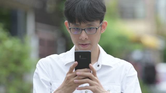 Junge-asiatische-Geschäftsmann-mit-Telefon-in-den-Straßen-im-freien