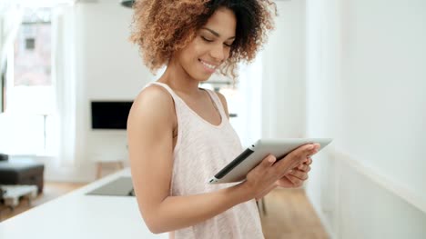 Smiling-happy-Afro-American-woman-using-pc-tablet-at-home.