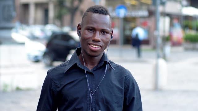lächelnde-schwarze-Amerikaner-hören-Musik-und-bewegen-in-der-Straße