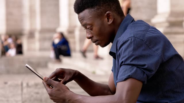 Attraktive-junge-Afrikaner-Usig-Tablet-im-freien-Profil