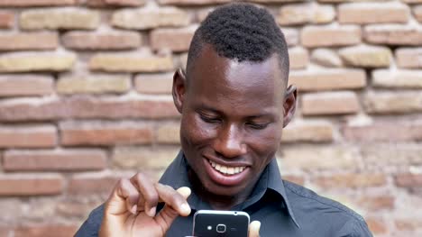 Retrato-de-sonriente-hombre-africano-americano-desplazamiento-su-smartphone.-Tecnología,-comunicación,