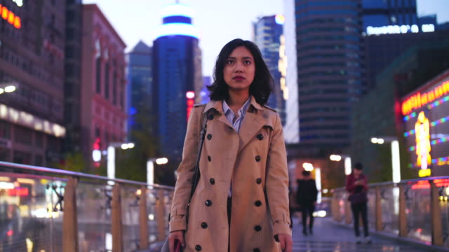 Zeitlupe-einer-ziemlich-glücklich-junge-asiatische-Frau-zu-Fuß-in-die-Stadt,-die-Straße-am-Abend