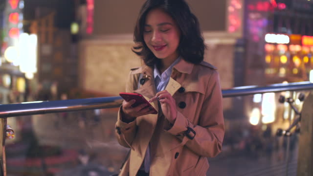 slow-motion--of-pretty-happy-young-asian-woman-using-mobile-phone-in-the-city-at-night
