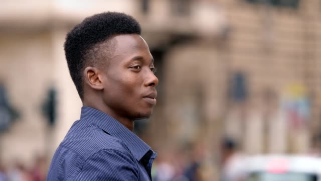 Attraktive-junge-schwarzen-afrikanischen-Mann-drehen-und-lächelnd-an-Kamera-outdoor