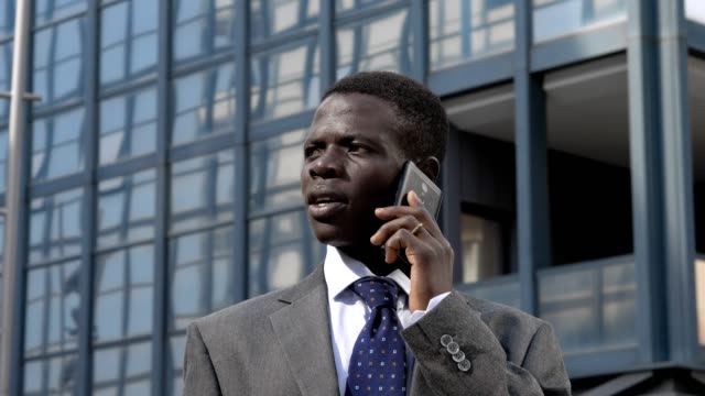 Erfolgreiche-zuversichtlich-schwarzen-amerikanischen-Geschäftsmann-Gespräch-per-Telefon-in-der-Straße