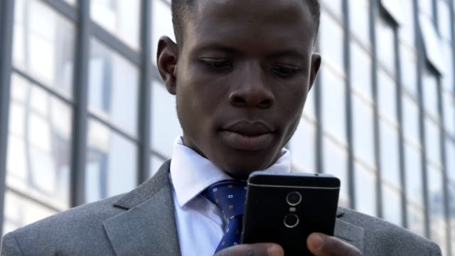 close-up-portrait-of-Busy-black-american-business-man-typing-on-his-smartphone-in-the-street