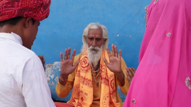 Indischer-Heiliger-Mann,-Sadhu,-Hände-hob-und-Segen-ein-paar-mit-gefalteten-Händen-in-Pushkar,-Rajasthan-Mann-Frau-Braut