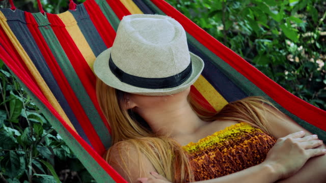Junge-Frau-mit-Hut-für-Gesicht-in-Hängematte-schlafen