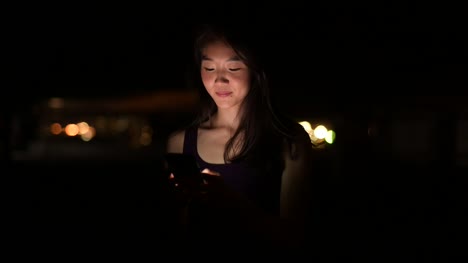 Beautiful-Asian-Woman-Outdoors-At-Night-Using-Mobile-Phone